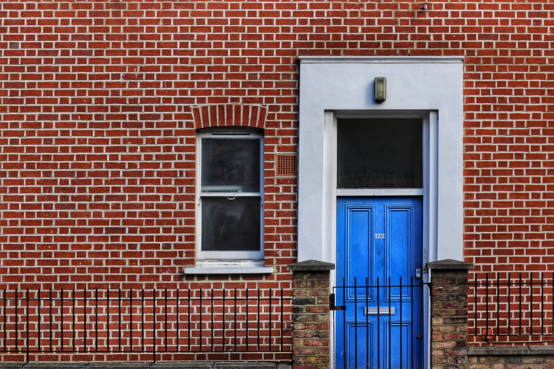 Stock photo of a London red-brick terraced house with a bright blue front door numbered 122